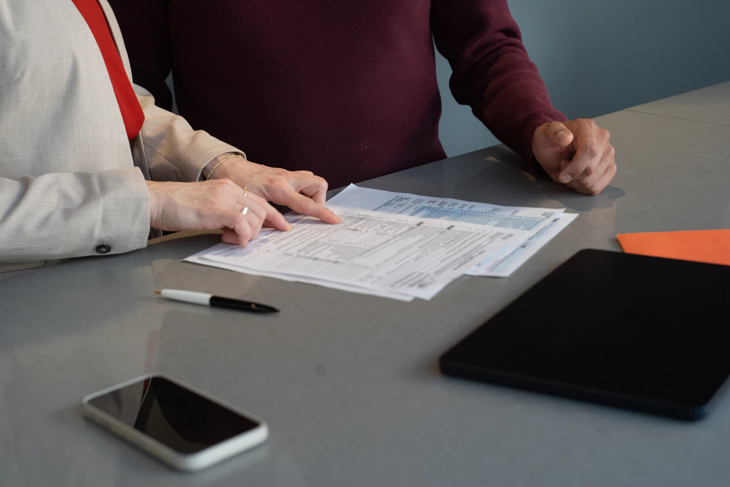 Due persone esaminano insieme un documento su un tavolo di lavoro.